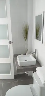 a white bathroom with a sink and a toilet at Coco Lodge Paracas in Paracas