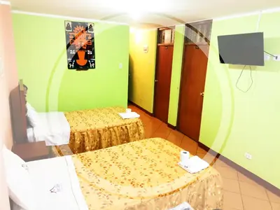 a hotel room with two beds and a tv at Hospedaje Las Lilas in Huancayo