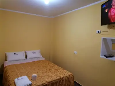 a small room with a bed and a flat screen tv at Hospedaje Las Lilas in Huancayo
