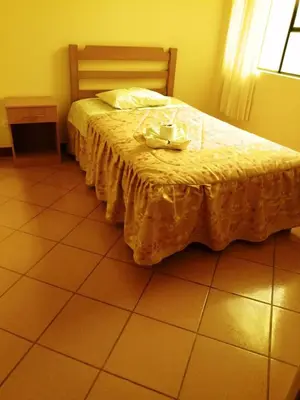 a bedroom with a bed with a yellow comforter at Hospedaje Las Lilas in Huancayo