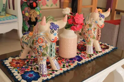 two figurines of cows on a table with a vase at Bull House in Urubamba