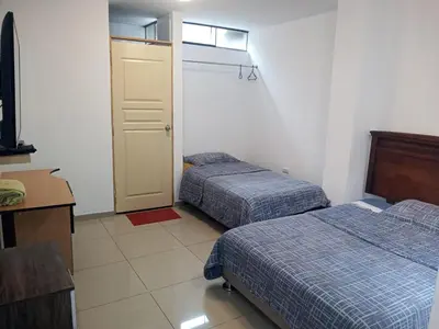 a hotel room with two beds and a door at Peruvian Family Hostal Miraflores in Lima