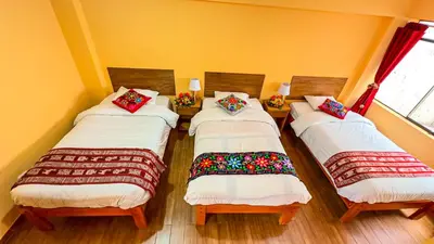 three beds in a room with yellow walls at Andean Atoq Hostel in Cusco