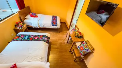 a view of a room with two beds and a mirror at Andean Atoq Hostel in Cusco