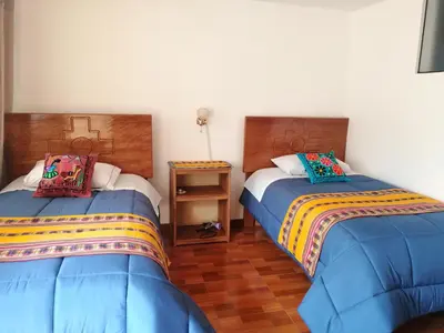 a bedroom with two beds and a night stand at Kenti's Home Ollantaytambo in Ollantaytambo