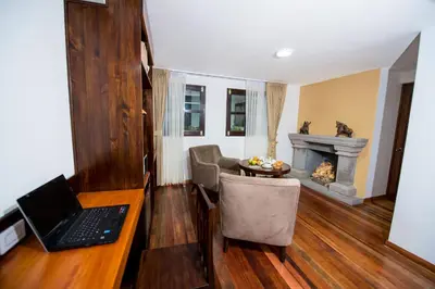 a living room with a laptop on a desk and a fireplace at Posada San Blas in Cusco