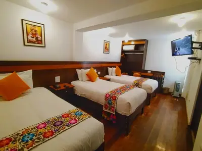 a hotel room with three beds and a flat screen tv at Posada San Blas in Cusco