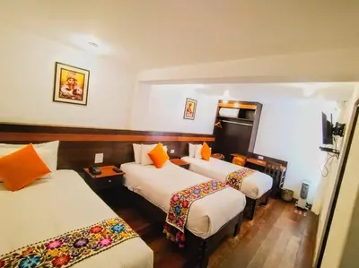 a hotel room with three beds with orange pillows at Posada San Blas in Cusco
