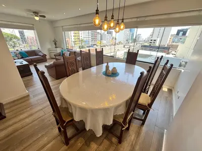 a dining room with a white table and chairs at Céntrico Apartamento Parque Kennedy Miraflores in Lima