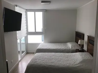 a bedroom with two beds and a flat screen tv at Moderno departamento Miraflorino con aire acondicionado in Lima