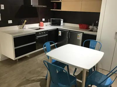 a kitchen with a white table and blue chairs at Moderno departamento Miraflorino con aire acondicionado in Lima