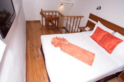a bedroom with a white bed with orange pillows at Hotel Arcangel in Cusco