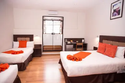 two beds in a room with orange pillows on them at Hotel Arcangel in Cusco