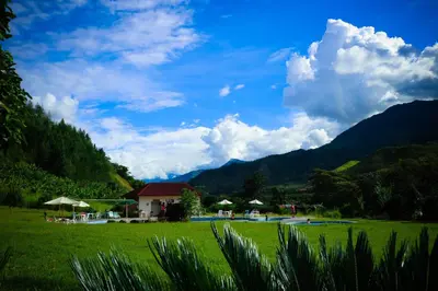 a green field with a house and mountains in the background at Mercedes Lodge in San Ramón