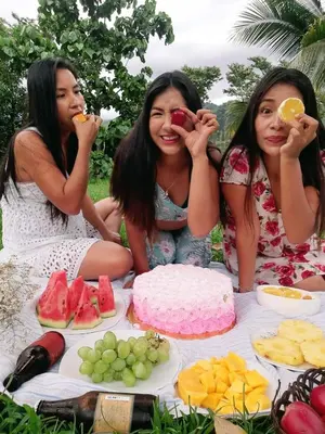 three girls are sitting at a picnic table with food at Mercedes Lodge in San Ramón