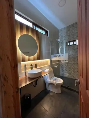 a bathroom with a toilet and a sink and a mirror at Mercedes Lodge in San Ramón