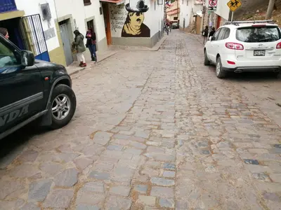 a cobblestone street with cars parked on it at Carlos Guest House 3 Cusco in Cusco