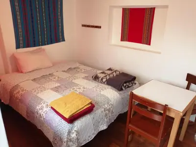 a small bedroom with a bed and a table at Carlos Guest House 3 Cusco in Cusco