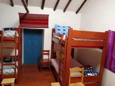 a room with two bunk beds and a door at Carlos Guest House 3 Cusco in Cusco