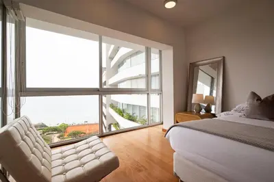 a bedroom with a bed and a large window at InkaHuset Miraflores Oceanfront in Lima