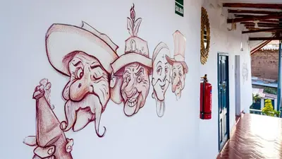 a wall with a drawing of faces on it at La Estación San Pedro in Cusco
