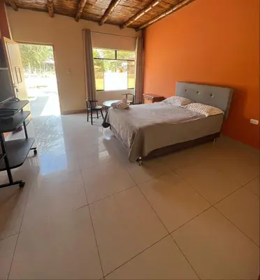 a bedroom with a bed and an orange wall at Hospedaje La Huega in Ica