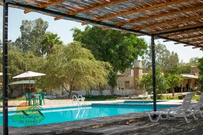 a swimming pool with chairs and an umbrella at Hospedaje La Huega in Ica