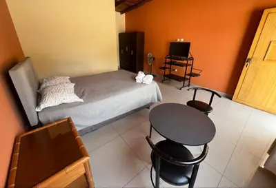 a bedroom with a bed and a table and chairs at Hospedaje La Huega in Ica
