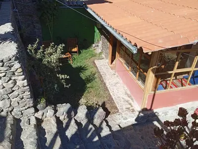 a house with a stone wall next to a building at Casa Inka B&B in Ollantaytambo