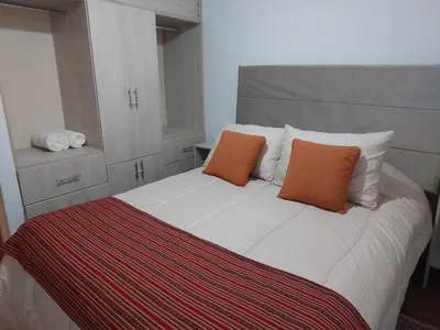 a white bed with two orange pillows on it at Pawllu Inqa Lodge in Cusco
