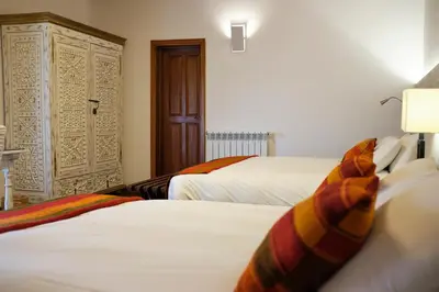 a hotel room with two beds and a closet at Tocuyeros Boutique Hotel in Cusco