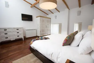 a bedroom with a white bed and a dresser at Tocuyeros Boutique Hotel in Cusco