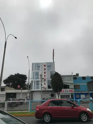 a red car driving down a street in front of a building at Hostal Parisuite in Lima