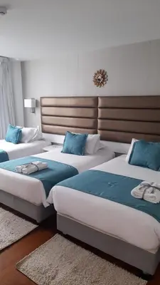 two beds in a hotel room with blue pillows at Katari Apart Hotel at Qorikancha in Cusco