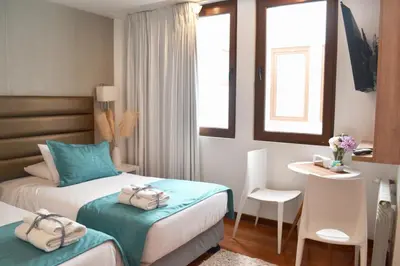 a hotel room with two beds and a table and a desk at Katari Apart Hotel at Qorikancha in Cusco
