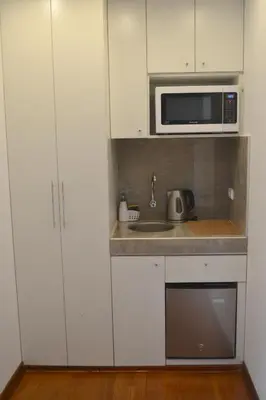 a kitchen with white cabinets and a sink and a microwave at Katari Apart Hotel at Qorikancha in Cusco