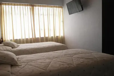 two twin beds in a bedroom with a window at Hostal Arias in Oxapampa