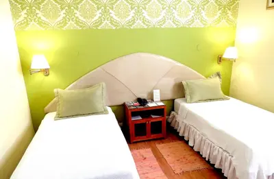 two beds in a room with green walls at Lima Wari Hotel Boutique in Lima