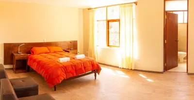 a bedroom with a bed with an orange blanket at Allin Illary Eco Hospedaje in Urubamba