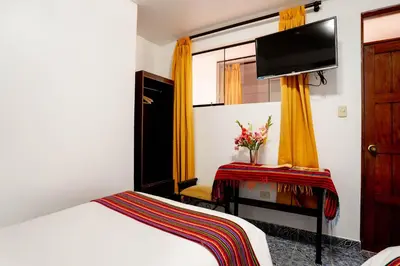 a bedroom with a bed and a tv on the wall at Hotel Machupicchu Inn in Machu Picchu