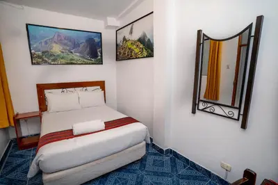 a small bedroom with a bed and two mirrors at Hotel Machupicchu Inn in Machu Picchu