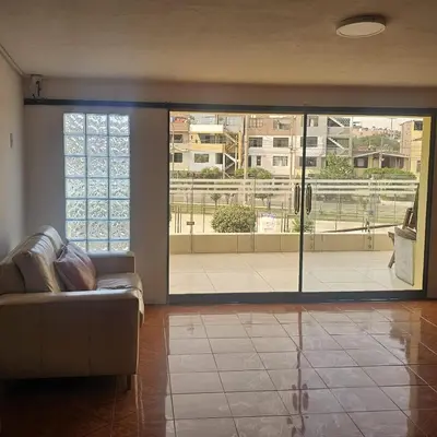 a living room with a couch and a large sliding glass door at Hostal Turístico El Cajamarquez in Lima