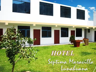 a white building with red doors and a green yard at Hotel Septima Maravilla Lunahuana in Lunahuaná