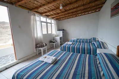 two beds in a room with a window at Hotel Puerto Inka in Chala