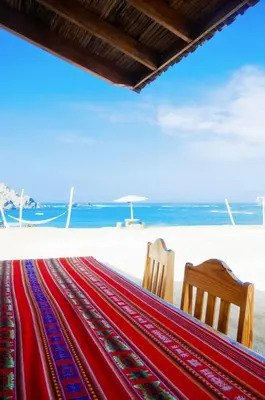 two chairs and a hammock on the beach at Hotel Puerto Inka in Chala
