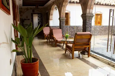 a porch with chairs and a table and a potted plant at Llamita Hotel-Huancayo in Huancayo