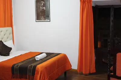 a bedroom with a bed with an orange blanket at Imperial Golden House Inn in Cusco