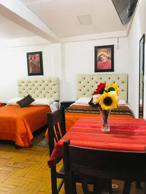 a room with two beds and a table with flowers on it at Imperial Golden House Inn in Cusco