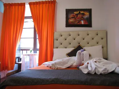 a bedroom with a bed with orange curtains at Imperial Golden House Inn in Cusco