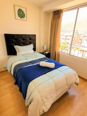 a bedroom with a large bed with a large window at Fiflos Apartament in Cusco